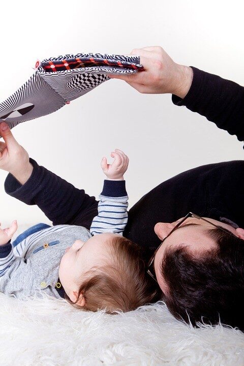 un uomo che tiene in braccio un bambino sdraiato sul pavimento