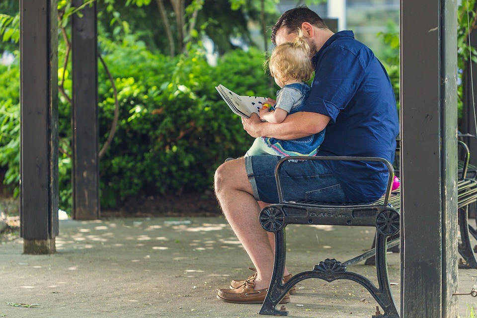 un uomo seduto su una panchina con in braccio un bambino