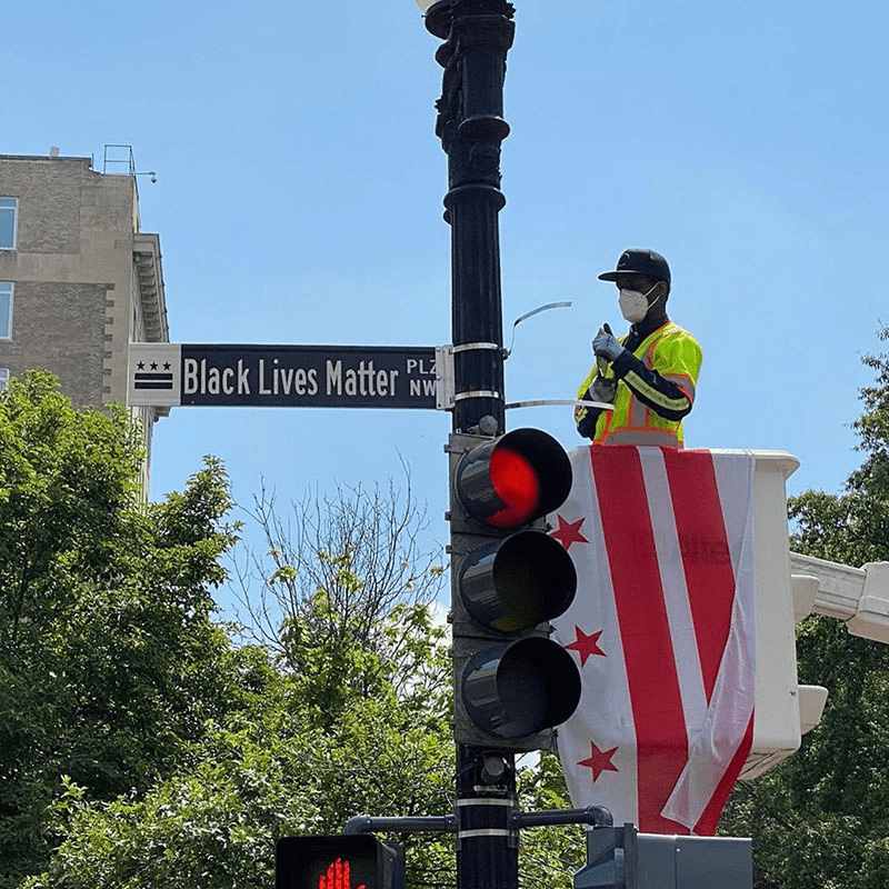 un uomo in piedi in cima a un semaforo accanto a un cartello stradale