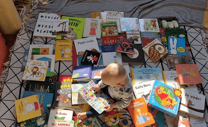 un bambino seduto su un letto con tanti libri