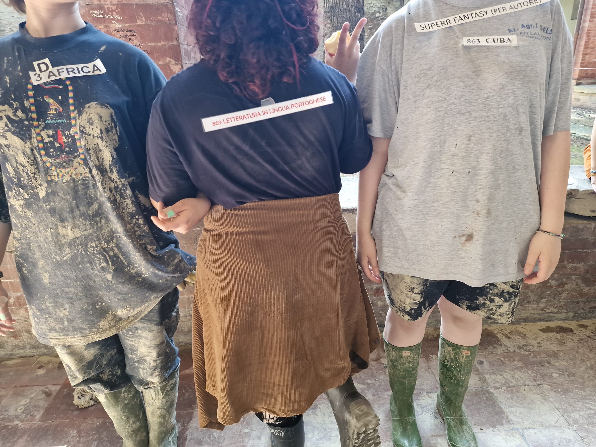 tre persone in piedi una accanto all'altra davanti a un muro di mattoni