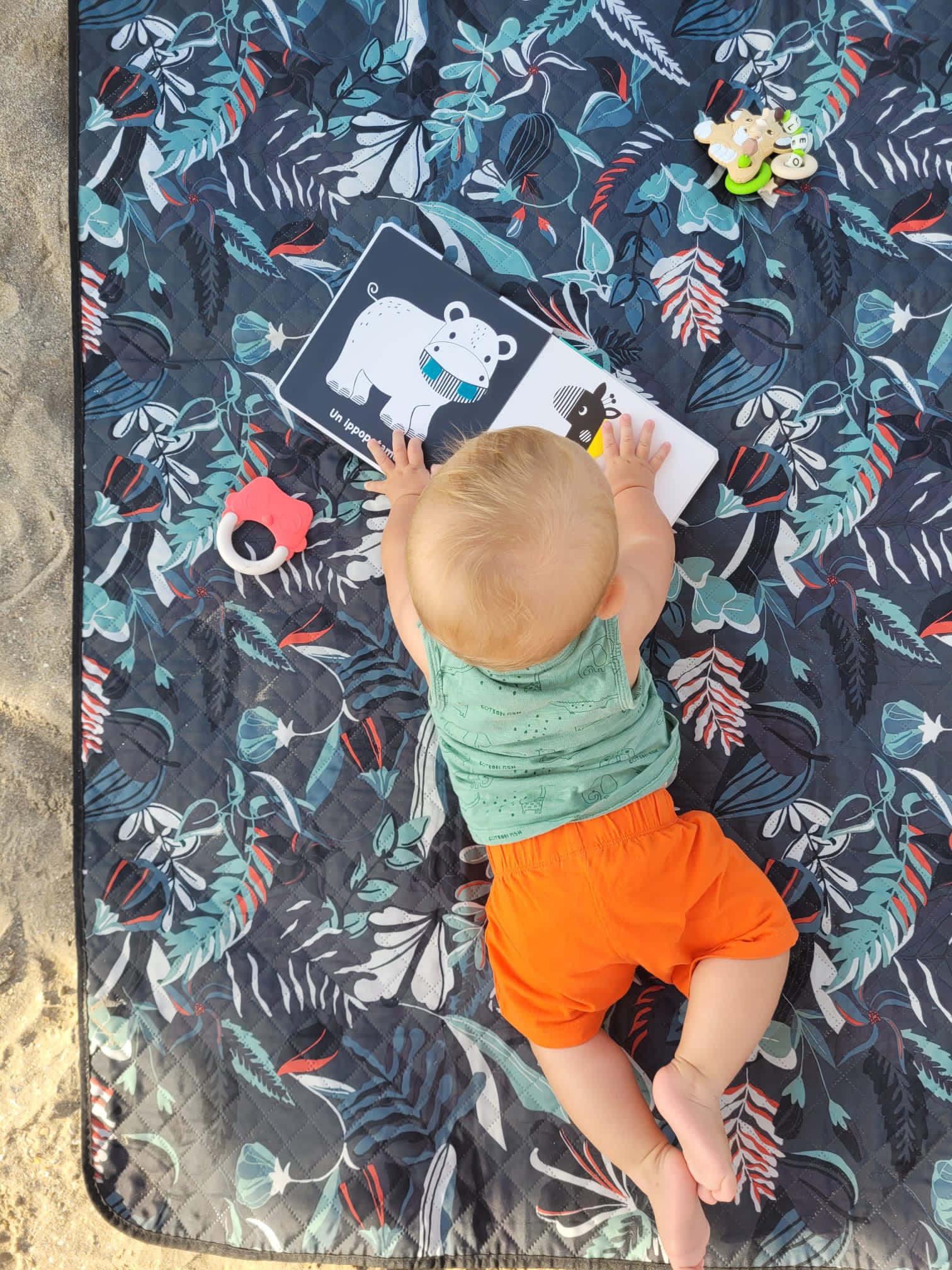 un bambino sdraiato su una coperta sulla spiaggia